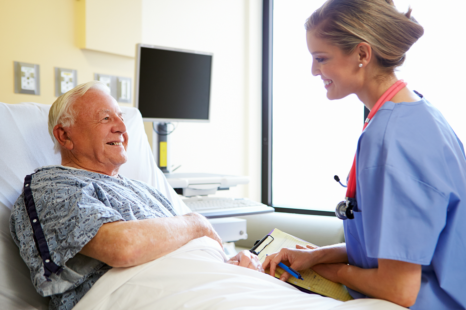 A doctor meets with a patient in a well-lit hospital room. 